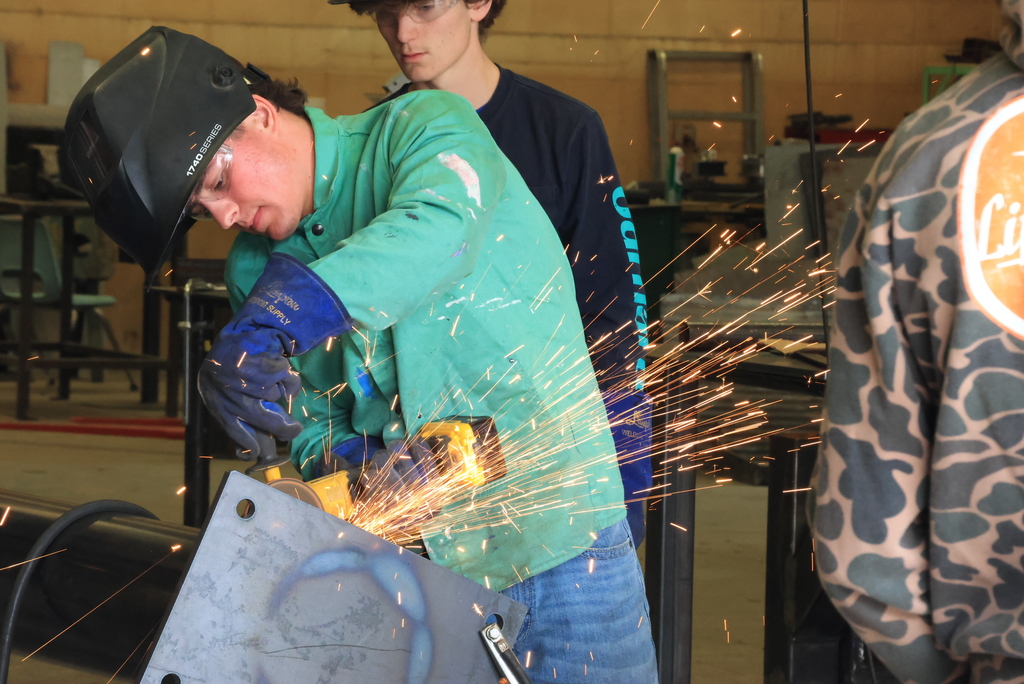 A student grinds the finished weld on the billboard stand.