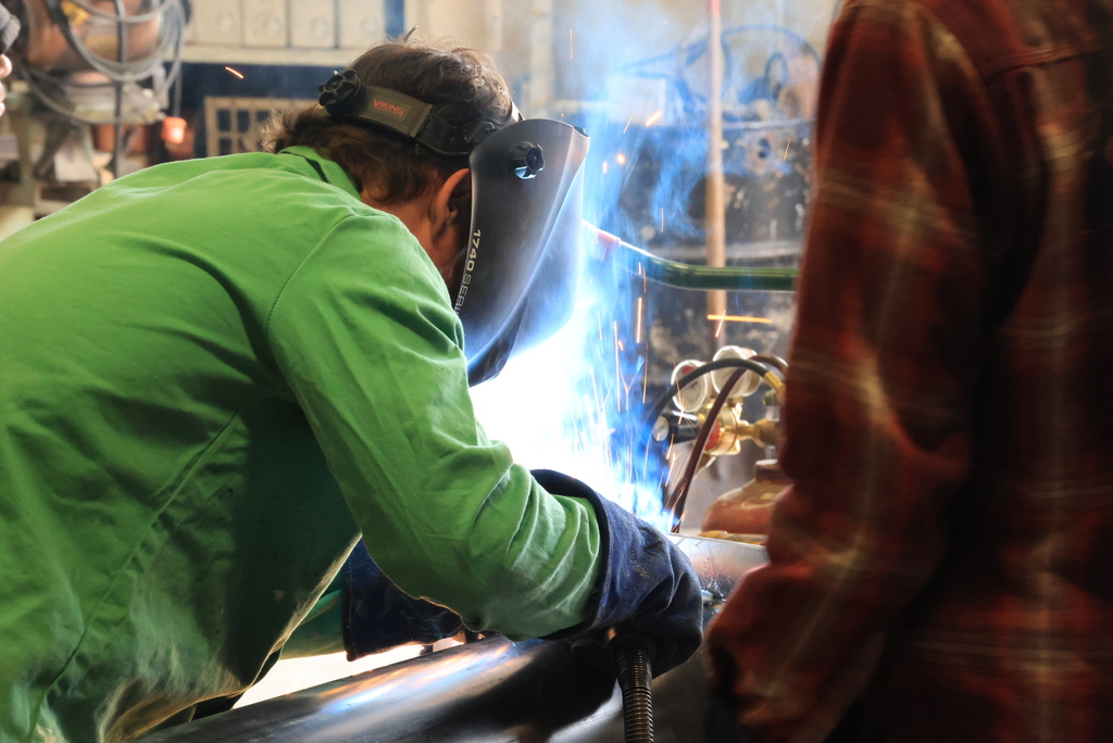 A student welds part of the billboard into place.