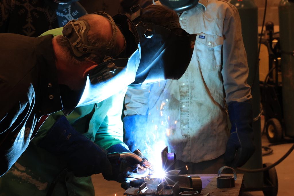 A student welds as Thomas Milligan looks on.
