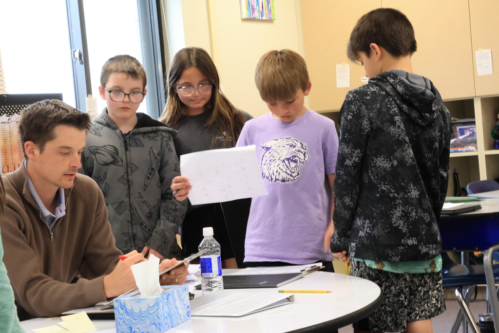 Mr. Wichman checks the progress of students who have answered comprehension questions.