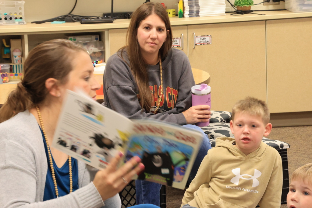 Mrs. Siebold reads a book to her class as they look on.