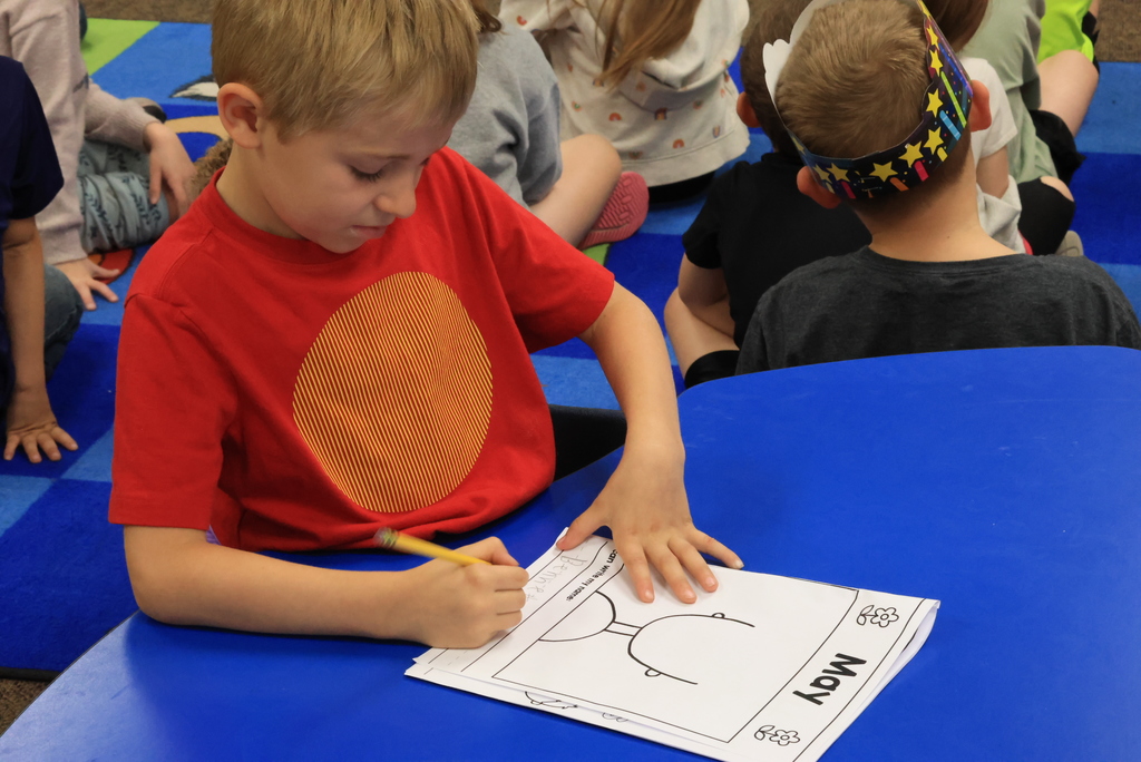 A student writes his name on a coloring assignment.