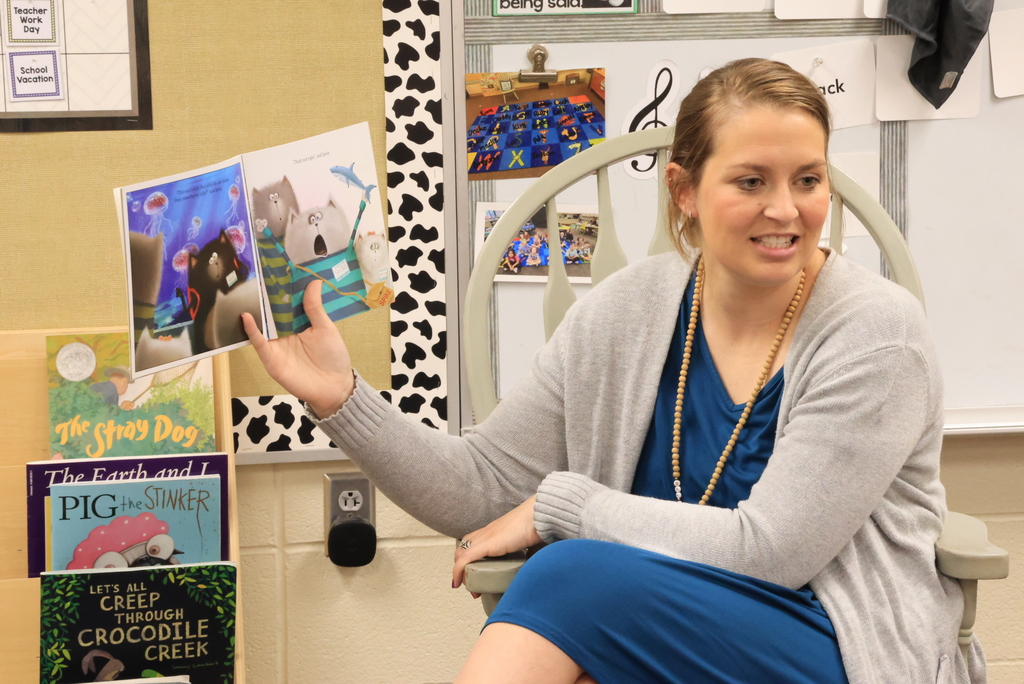 Mrs. Siebold reads a book to her class as they look on.