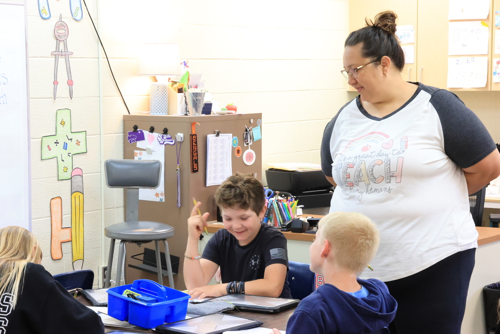 Students work on their "My Pretend Life" simulation while. Mrs. Baumann looks on.