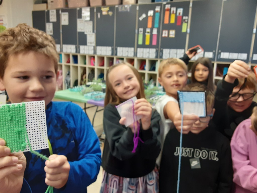 Members of Mrs. Carr's class show off their sewing canvas creations, which they have been working on as part of their soft start mornings.