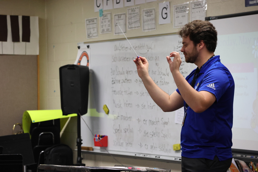 Band teacher Mr. Eyermann directs his 8th grade students with a baton in his hand.