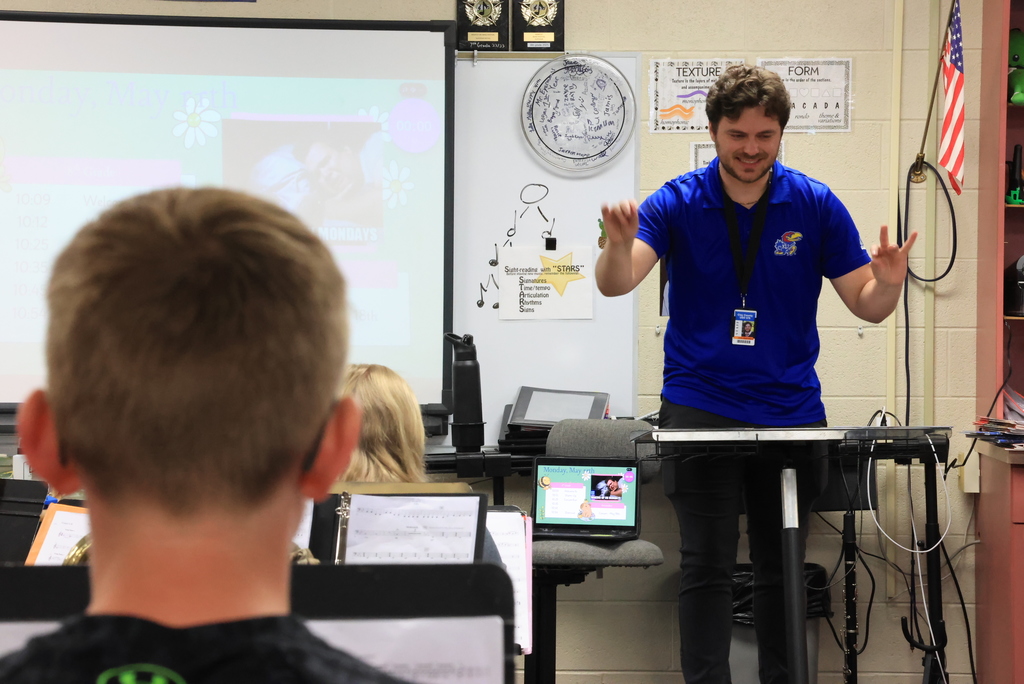 Band teacher Mr. Eyermann directs his 8th grade students with a baton in his hand.