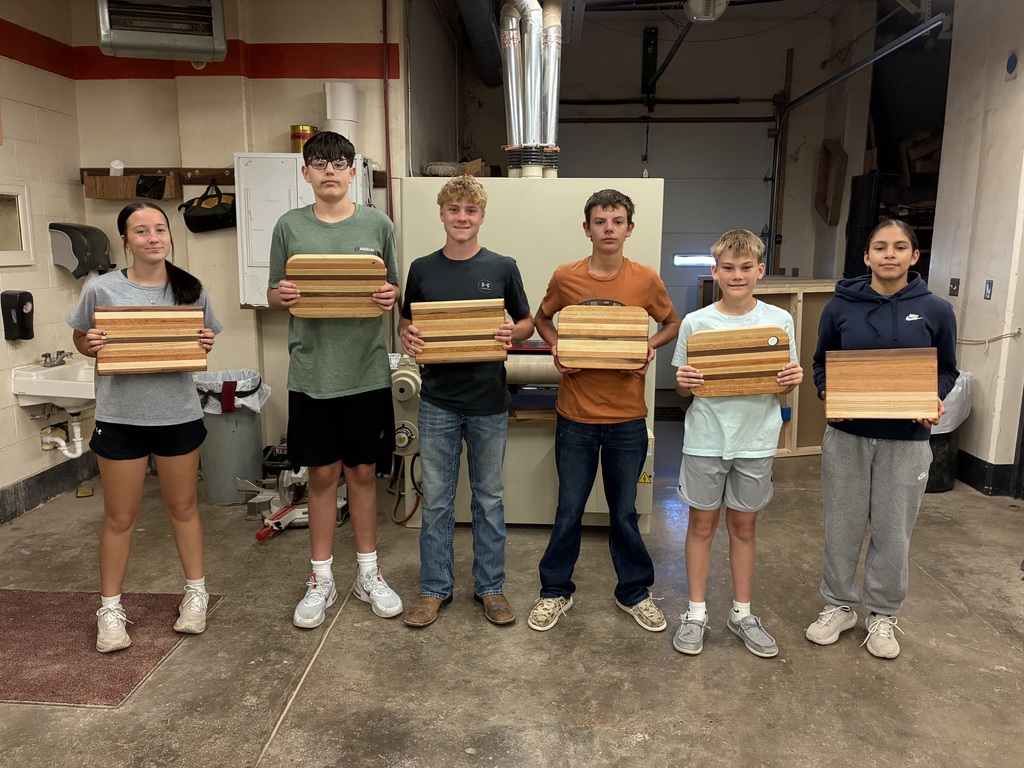 Six 8th grade industrial arts students show off their completed cutting boards.