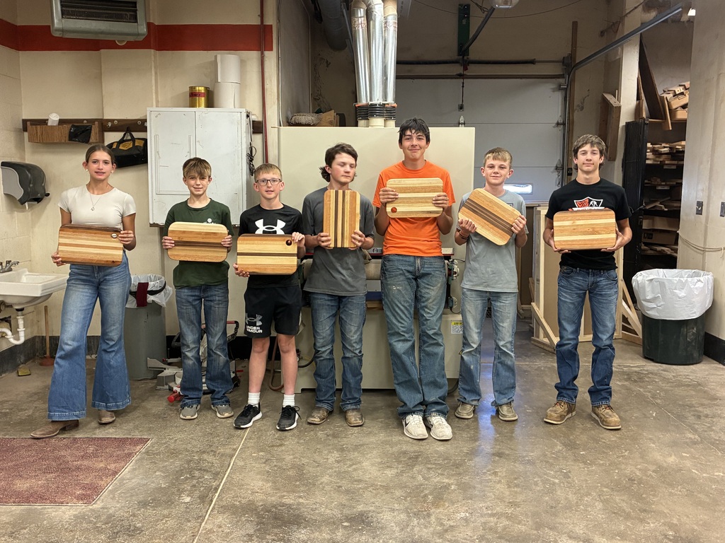 Seven 8th grade industrial arts students show off their completed cutting boards.