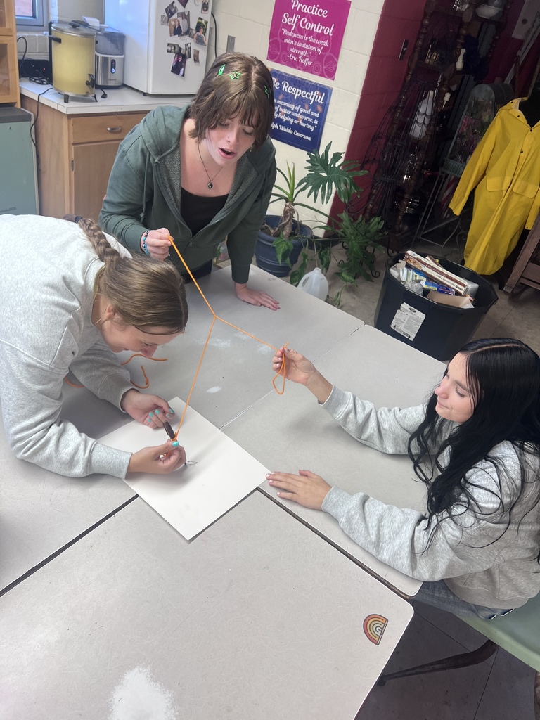 Mrs. Blackburn's debate team attempts to draw an image on the screen using teamwork with string and a marker.