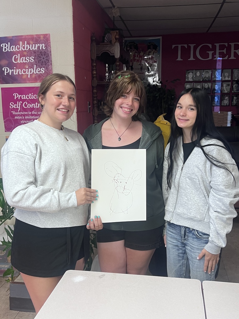 Mrs. Blackburn's debate team attempts to draw an image on the screen using teamwork with string and a marker.