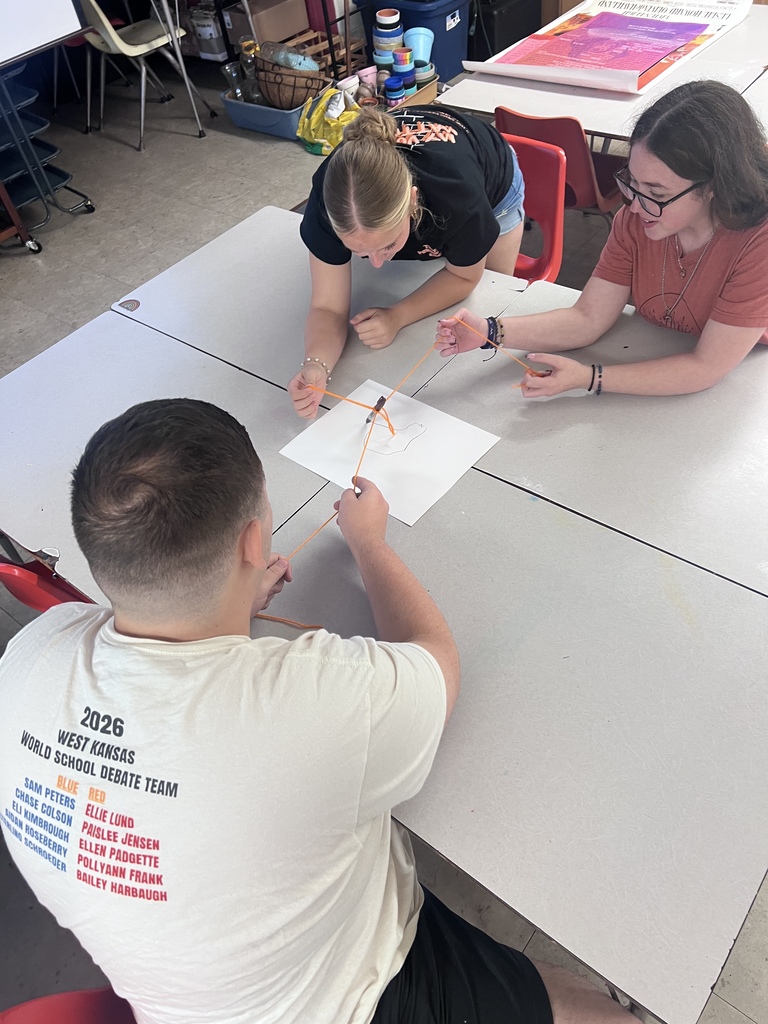 Mrs. Blackburn's debate team attempts to draw an image on the screen using teamwork with string and a marker.