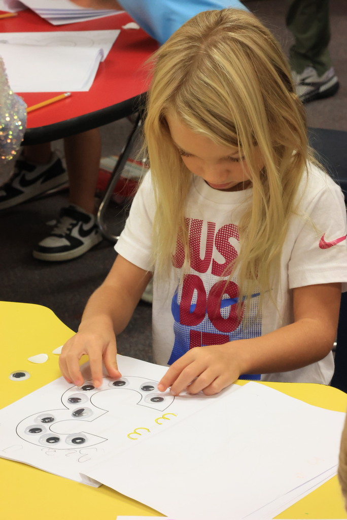 Students learn how to put googly eyes on to their number chart.