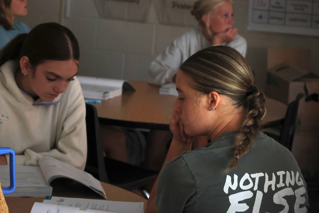 Ms. Smith teaches her 8th grade ELA students the definition of a participle while they write notes.