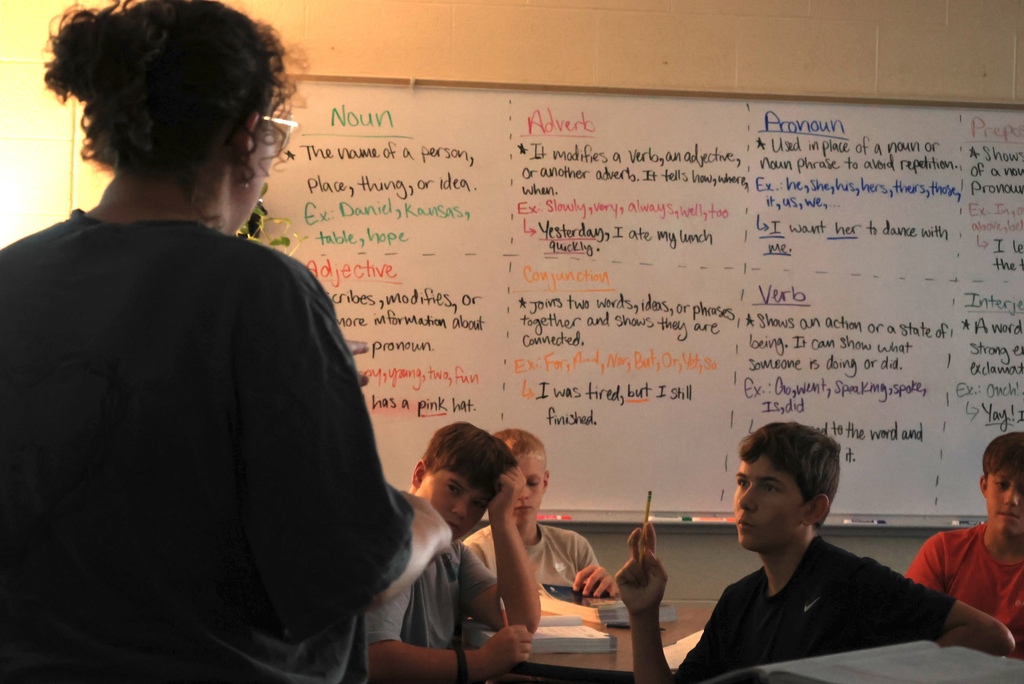 Ms. Smith teaches her 8th grade ELA students the definition of a participle while they write notes.