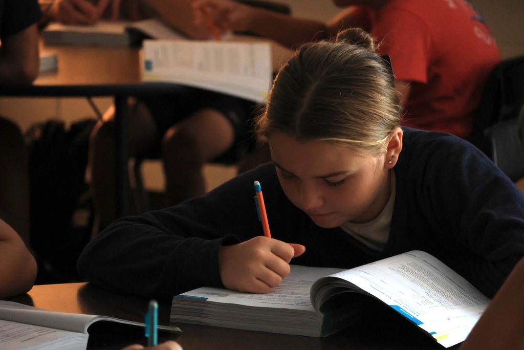 Ms. Smith teaches her 8th grade ELA students the definition of a participle while they write notes.