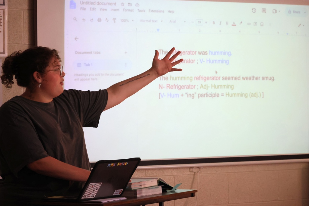 Ms. Smith teaches her 8th grade ELA students the definition of a participle while they write notes.