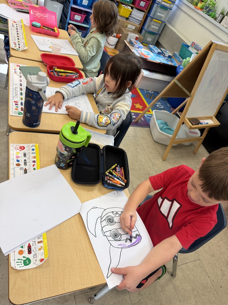 The K-1 class colors in their new art books created by the middle and high school art students.