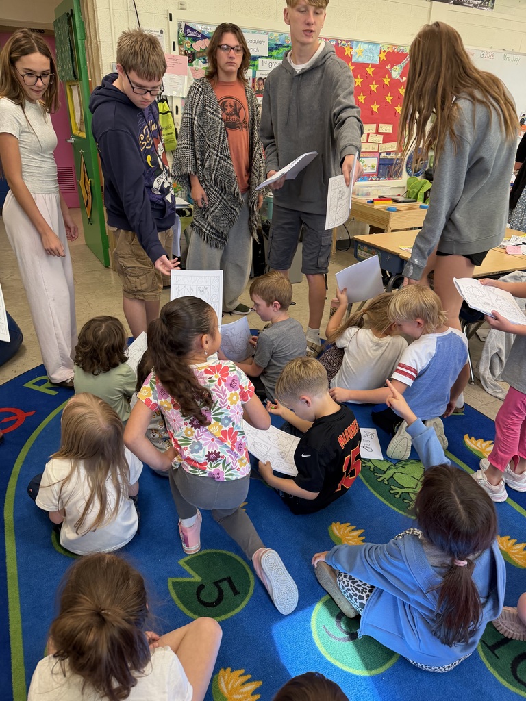 The K-1 class colors in their new art books created by the middle and high school art students.
