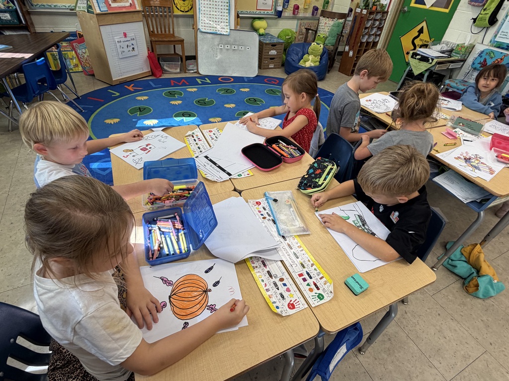 The K-1 class colors in their new art books created by the middle and high school art students.