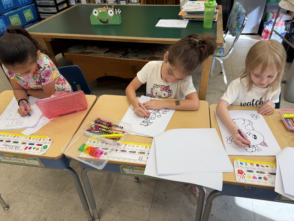 The K-1 class colors in their new art books created by the middle and high school art students.