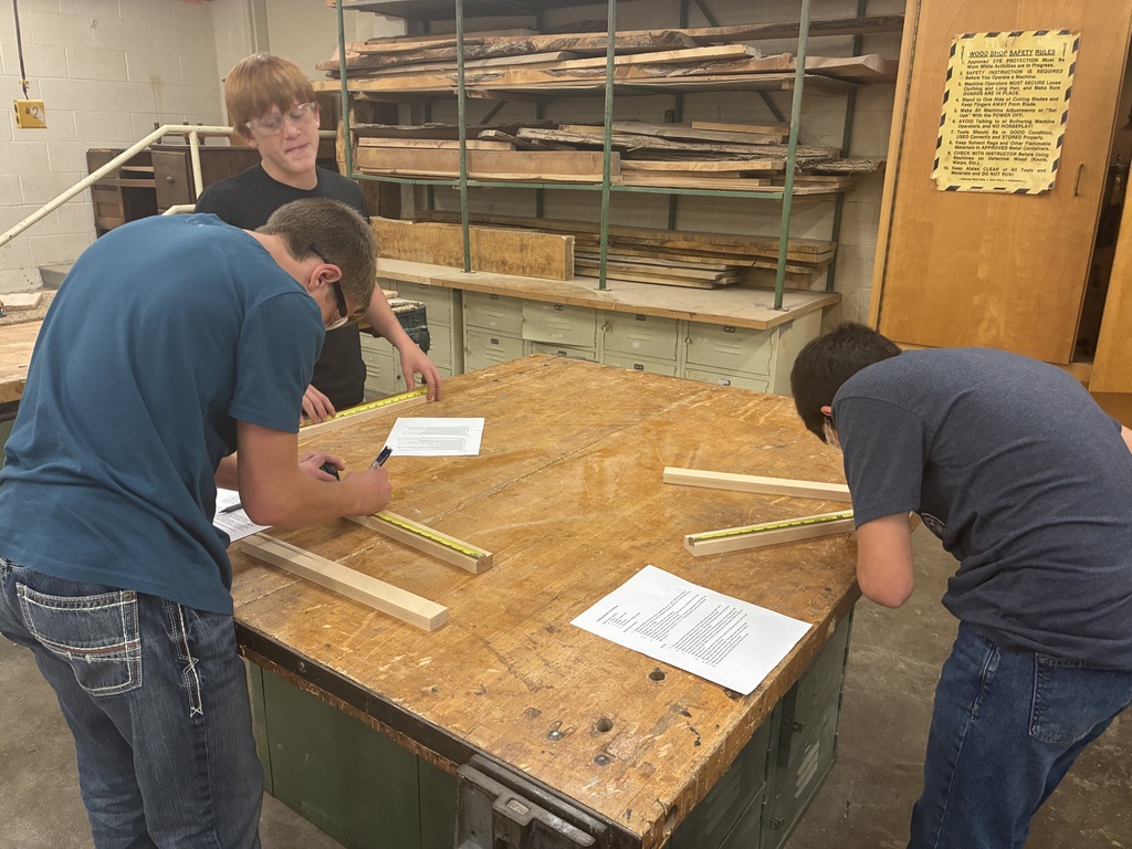 Mrs. Schooley's industrial arts students measure and cut boards.