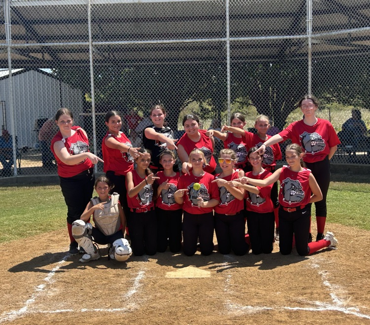 Softball team pointing at plaque