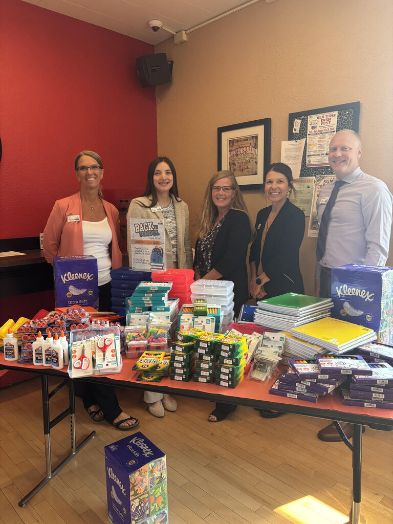 Bank Employees standing front of donated school supplies.
