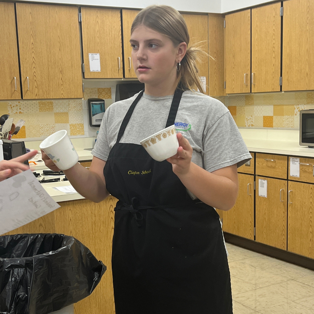 Student holding two cups in her hand in a kitchen at School.