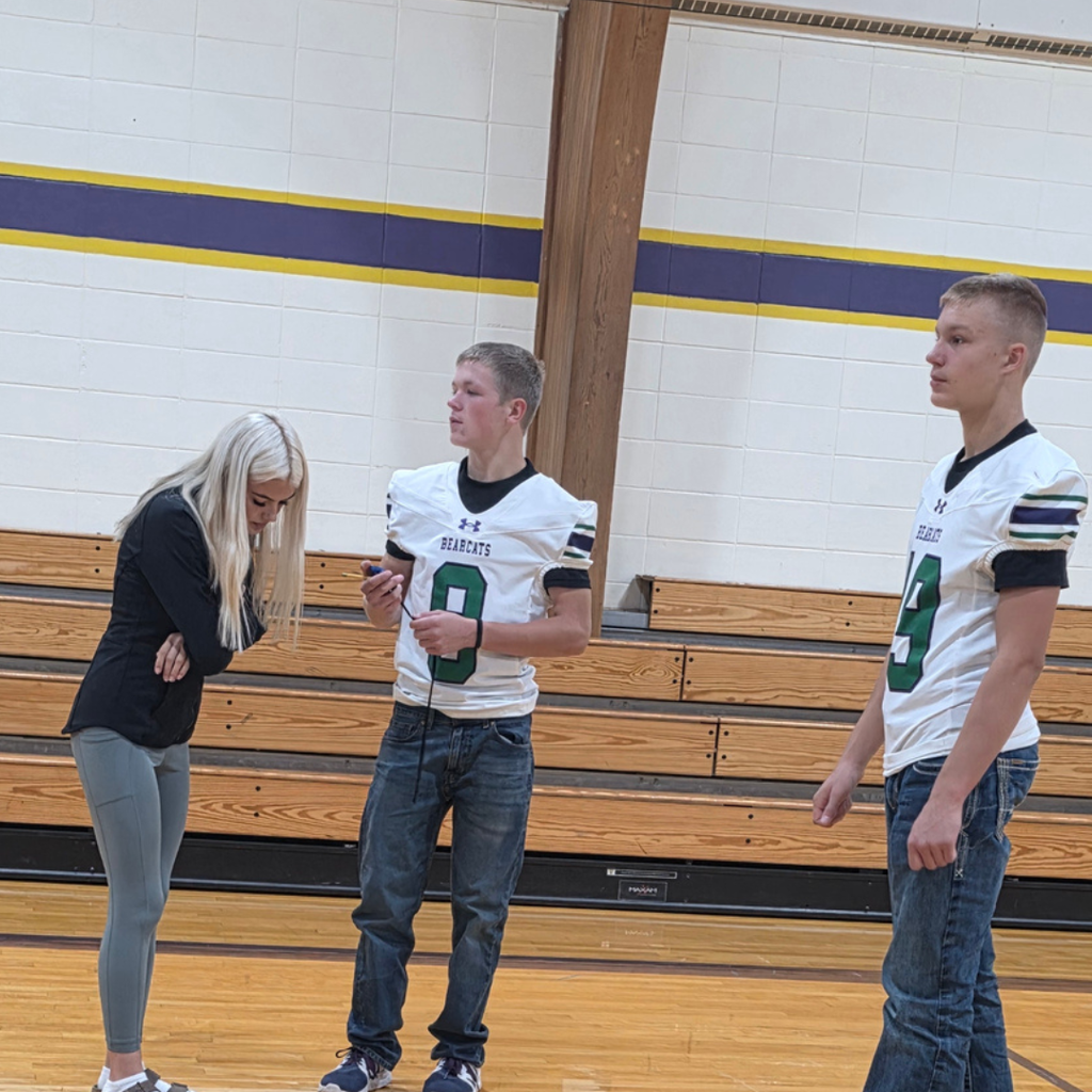 Students standing in a gym testing speed on a ramp.