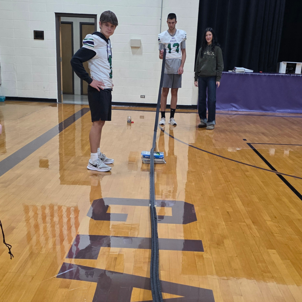 Students standing in a gym testing speed on a ramp.
