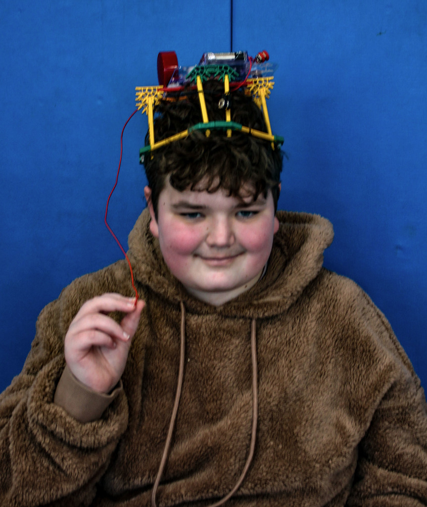 Student with an electrically engineered device on his head that connects to a radio and plays audio from it.