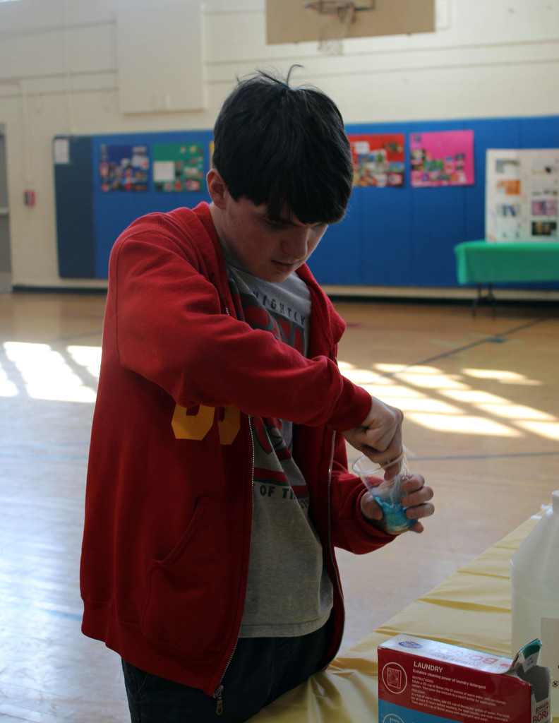 Student mixing together cornstarch, glue, and borax to create a blue bouncy ball.