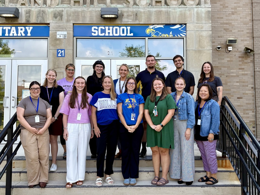 14 new teachers standing in front of building