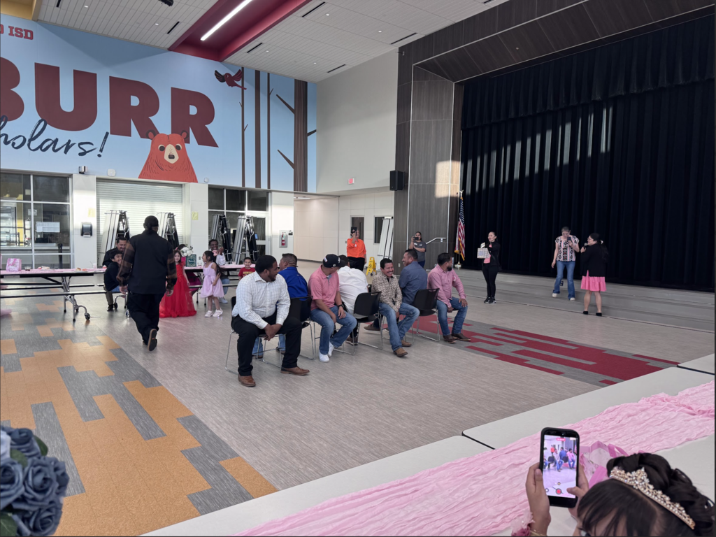 Group of people sitting and standing in a room with a large banner reading "BURR Schools".