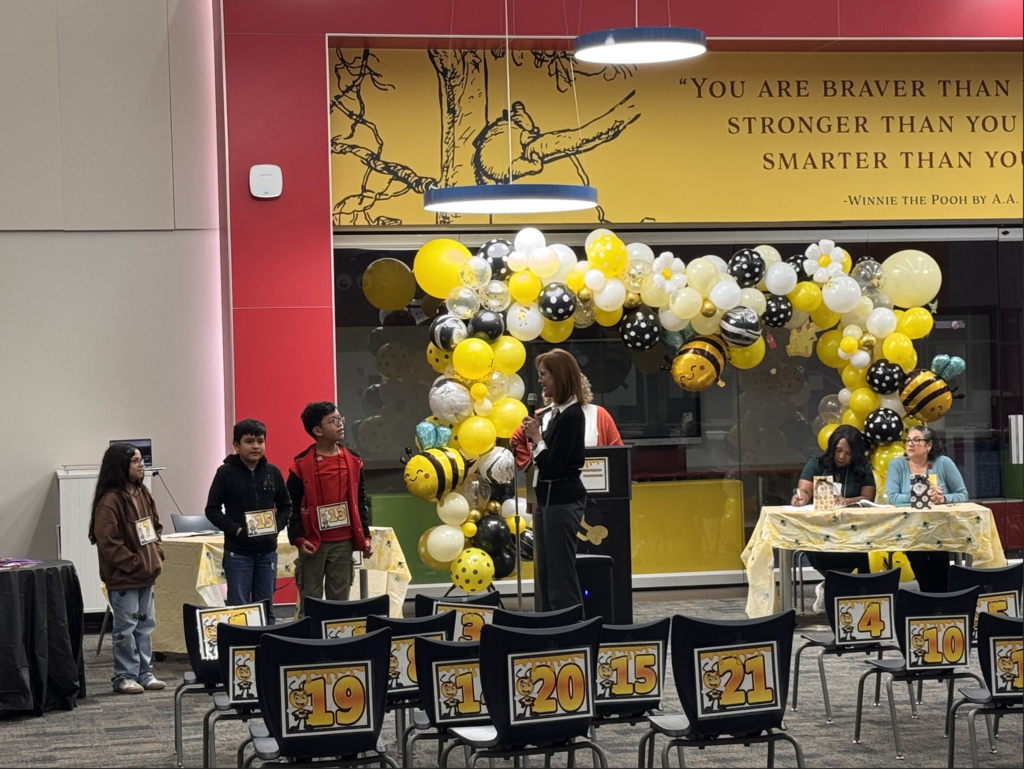 Event with balloons and chairs arranged in a room. A person stands at a podium. A banner reads, "You are braver than you think."