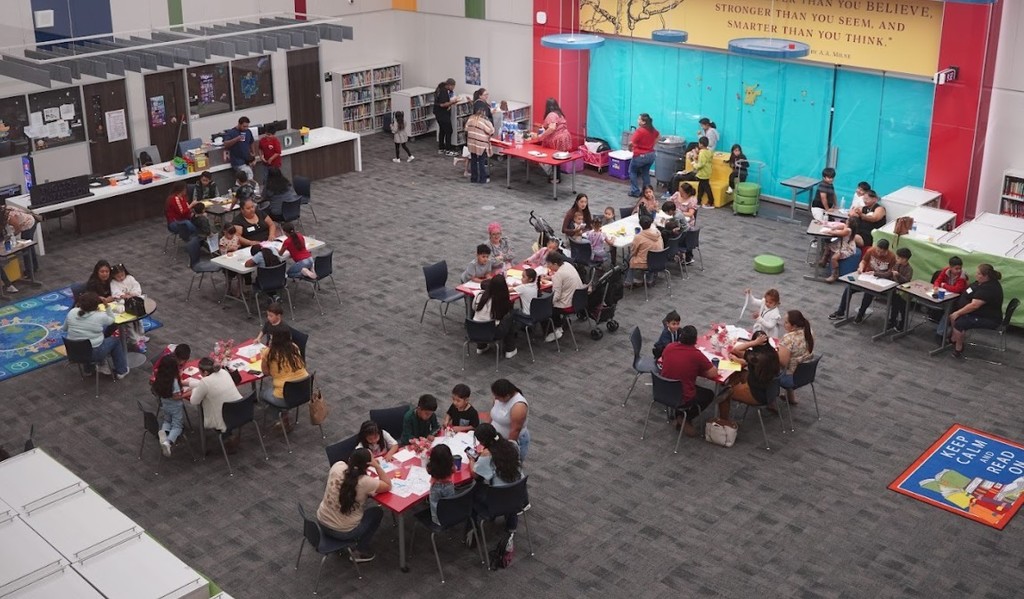 A cafeteria with people seated at tables, some standing, in a room with colorful walls.