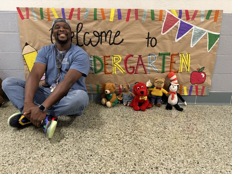 Mr. Shawn sitting beside Kindergarten sign.