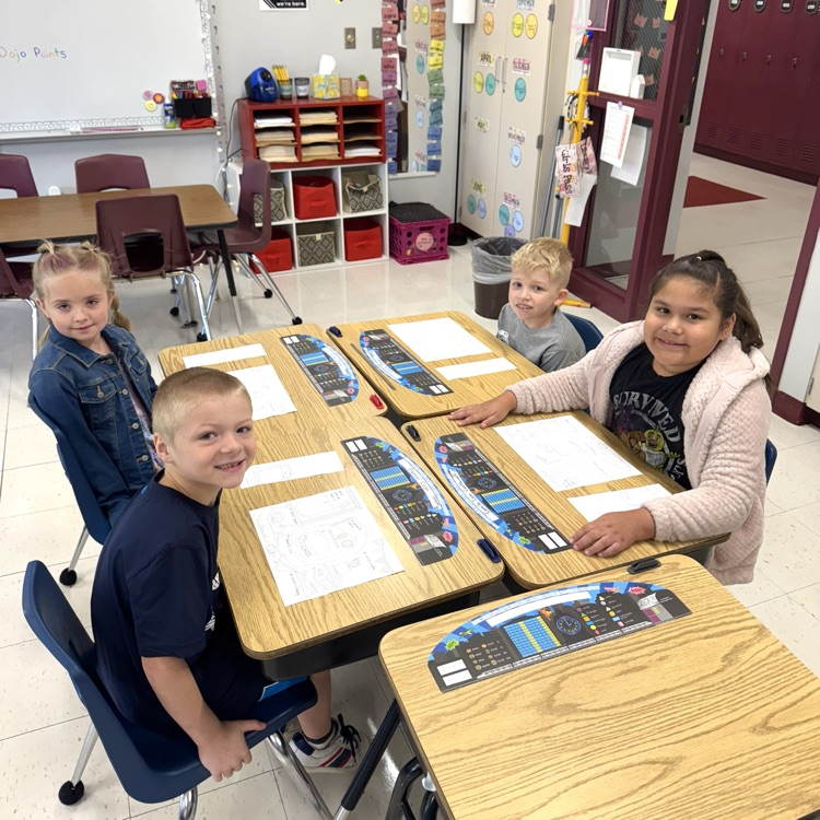 students smiling at group desk