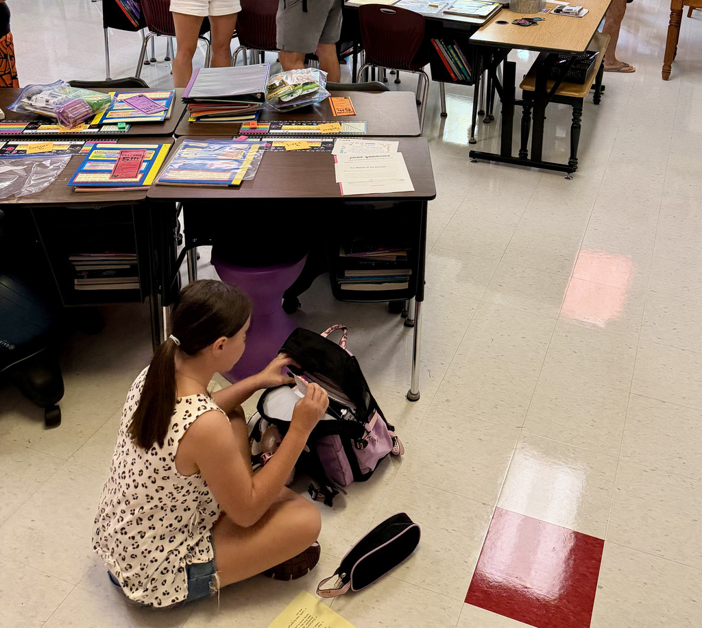 Student putting supplies in her desk