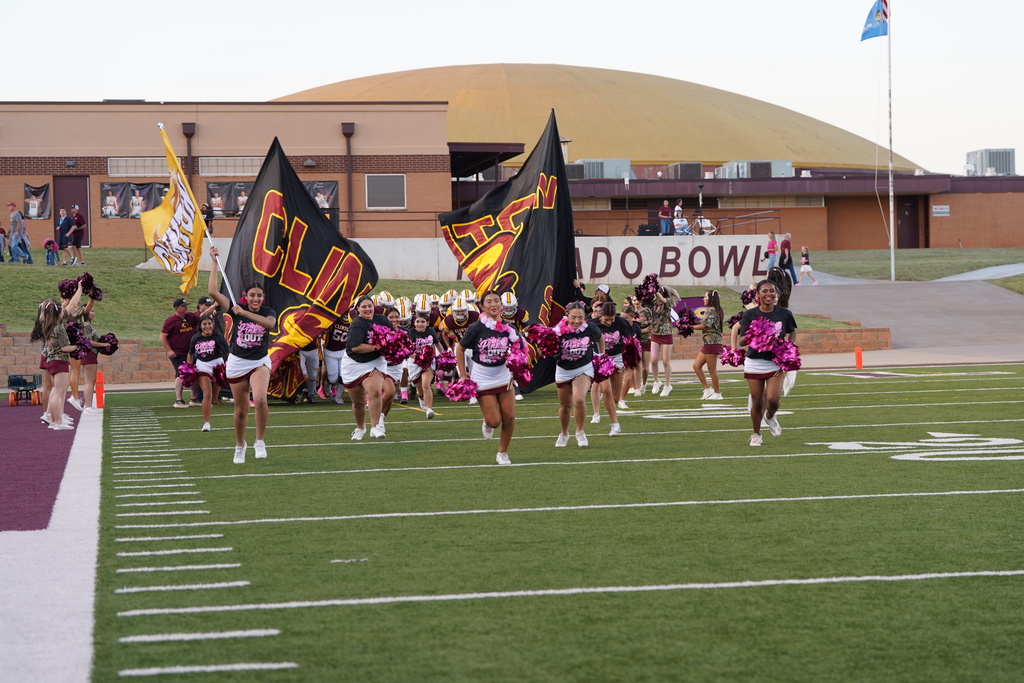 Football and Cheer running out at Pink Out