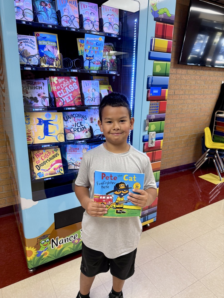 student holding a book in front of the book vending machine