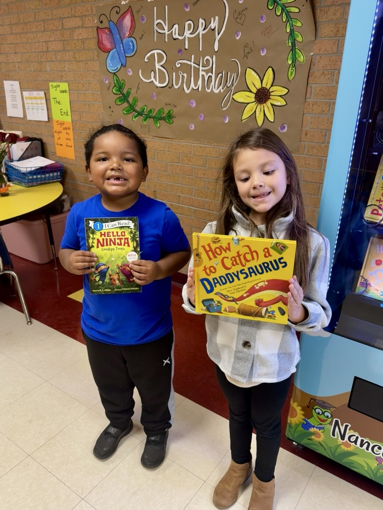 students holding a book in front of the book vending machine