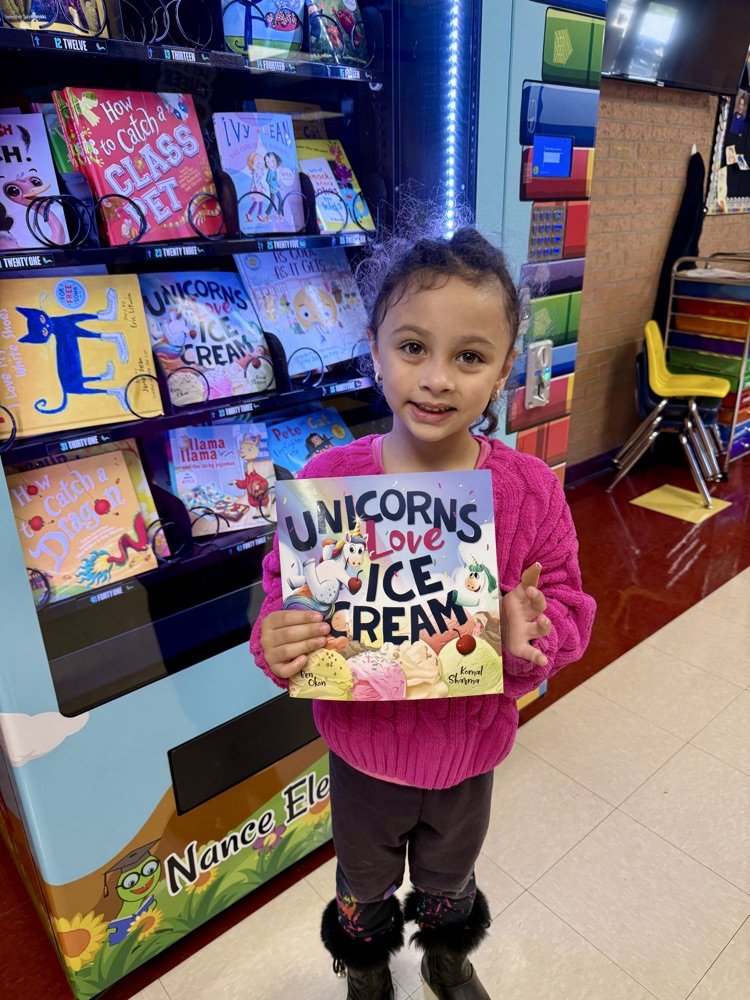 student holding a book in front of the book vending machine
