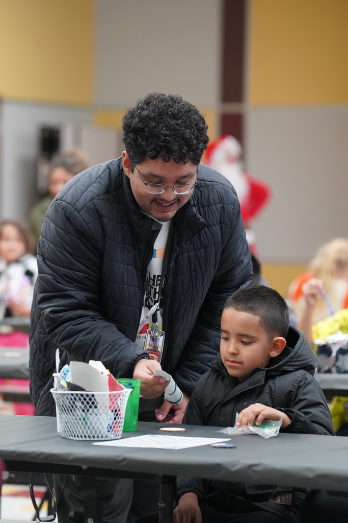 Teacher helping a student make an ornament