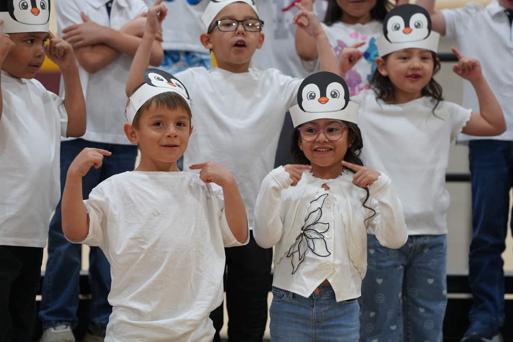 Students smiling wearing penquin hats