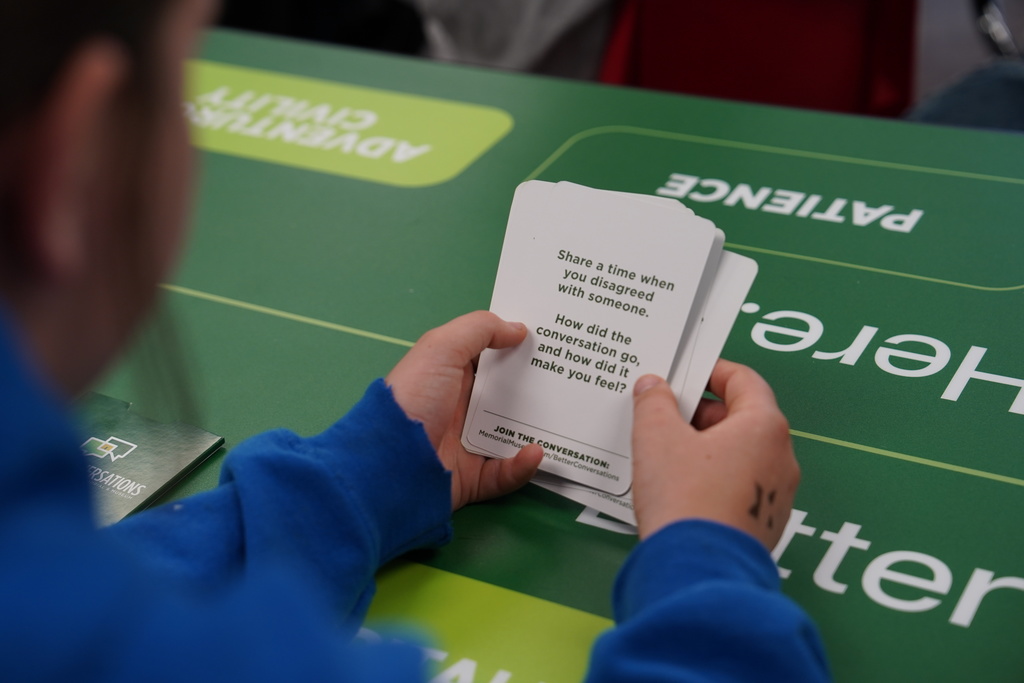 Student holding better conversation card