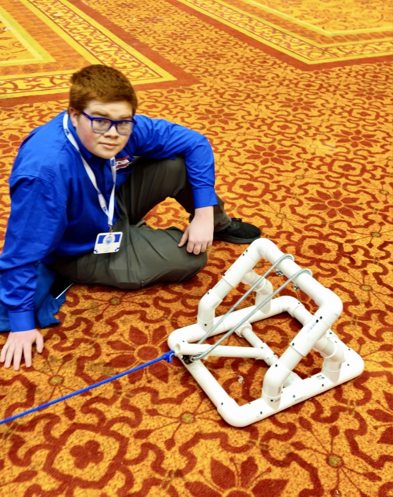 Student sitting on floor with catapult