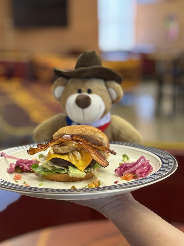 Stuffed bear looking at a burger