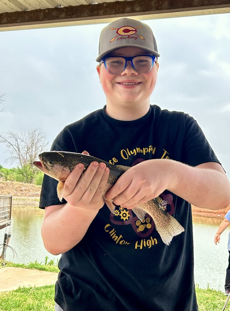 student smiling while holding a fish 